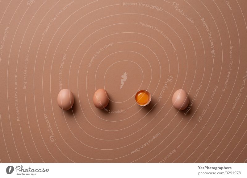 Organic eggs and one cracked egg with yolk. Aligned eggs Nutrition Diet Healthy Eating Fresh Natural above view aligned brown background brown eggs chicken eggs