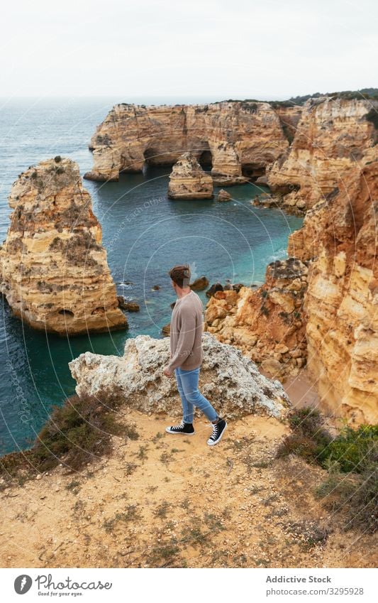 Unrecognizable man on cliff near sea admire nature travel rock landscape freedom portugal male ocean tourism trip journey wanderlust stone rough edge hiking