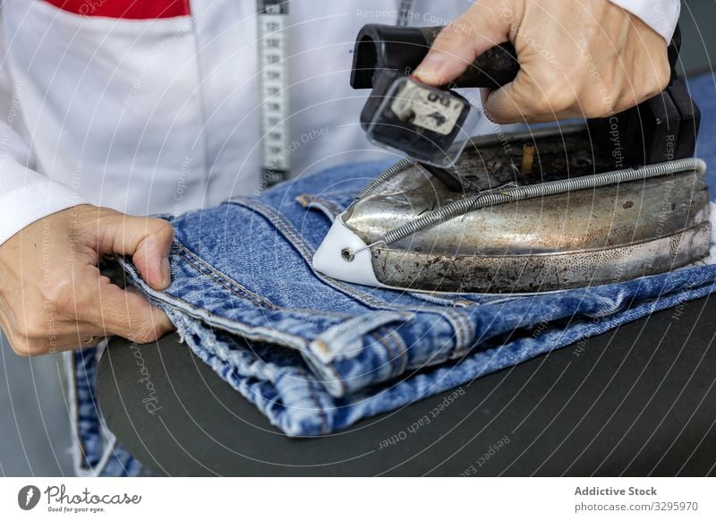 Woman's hands in textile factory ironing on industrial sewing machine. industry clothing manufacturing worker woman fabric pants blue jeans occupation