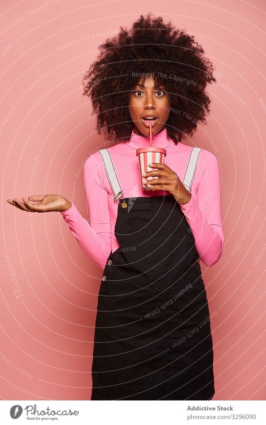 Happy black woman with disposable cup of drink standing against pink background happy straw african american laugh cheerful gesture ethnic female young casual