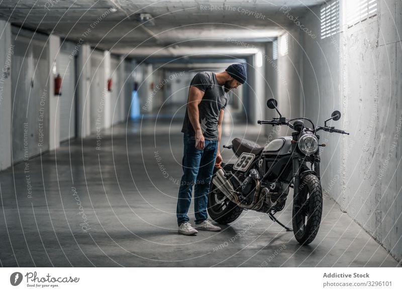 Bearded biker in garage hallway motorcycle man modern standing confident bearded transport ride male vehicle motorbike city urban corridor contemporary facility