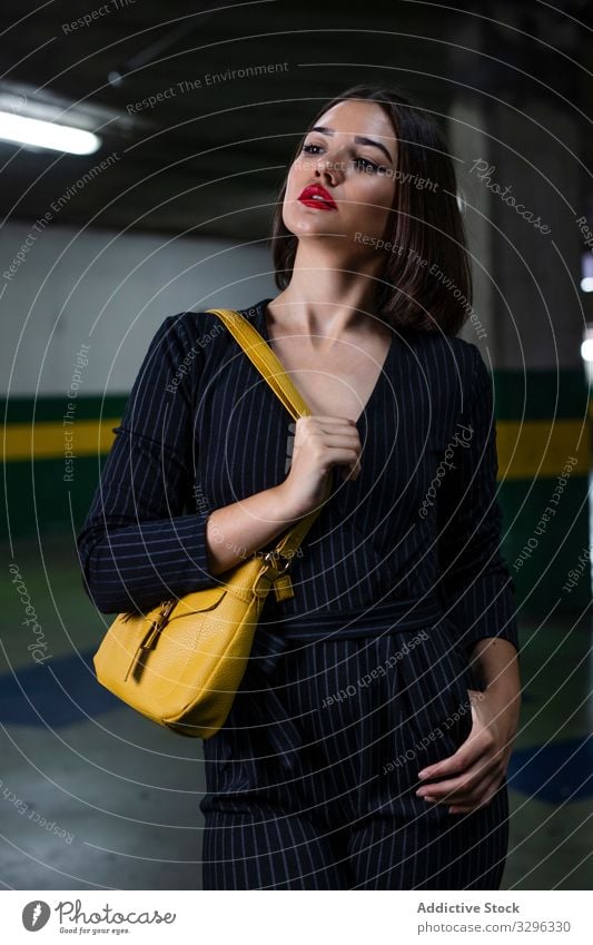 Woman in stylish outfit at a car parking woman fashionable trendy dusk shadow clothing city street standing young cap lady brunette accessory modern female