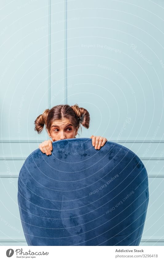 Scared teenage girl in a blue armchair scared female fashion sitting posing turquoise studio comfortable elegance home room portrait expression furniture