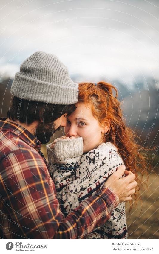 Charming red haired woman embracing man in mountains with closed eyes couple hugging bonding amorous romantic relationship lawn travel adventure tender