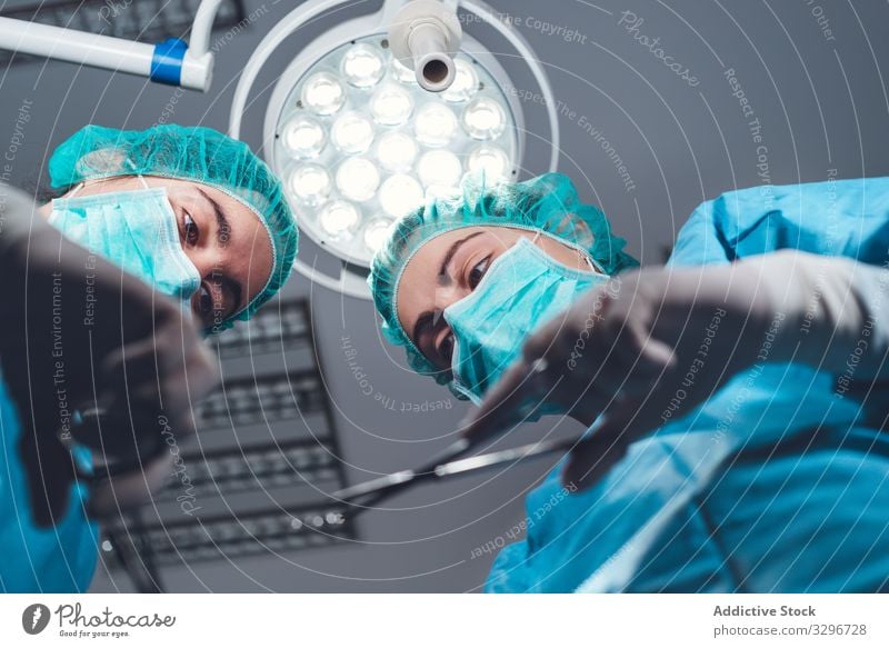 Women performing surgery in hospital together surgeon operating theater lamp tool mask hat women work doctor healthcare female sterile instrument colleague job