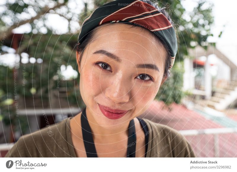 Satisfied Asian resting female in casual wear having relaxation at tropical hotel woman vacation resort smile enjoy summer season green plant young lady