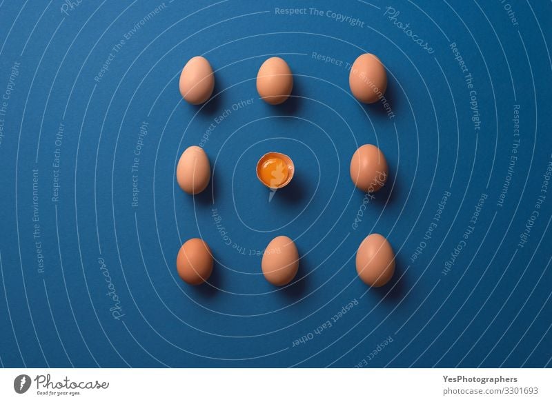 Whole eggs and one cracked egg yolk. Organic brown eggs Nutrition Diet Healthy Eating Fresh Natural above view aligned Blue background chicken eggs easter eggs