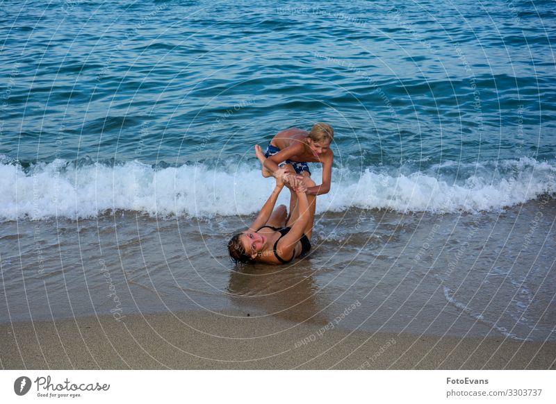 Two funny children play together on a beach in front of a sea wave two Brothers and sisters brother and sister Beach Sandy beach Ocean people Fight Funny Joy