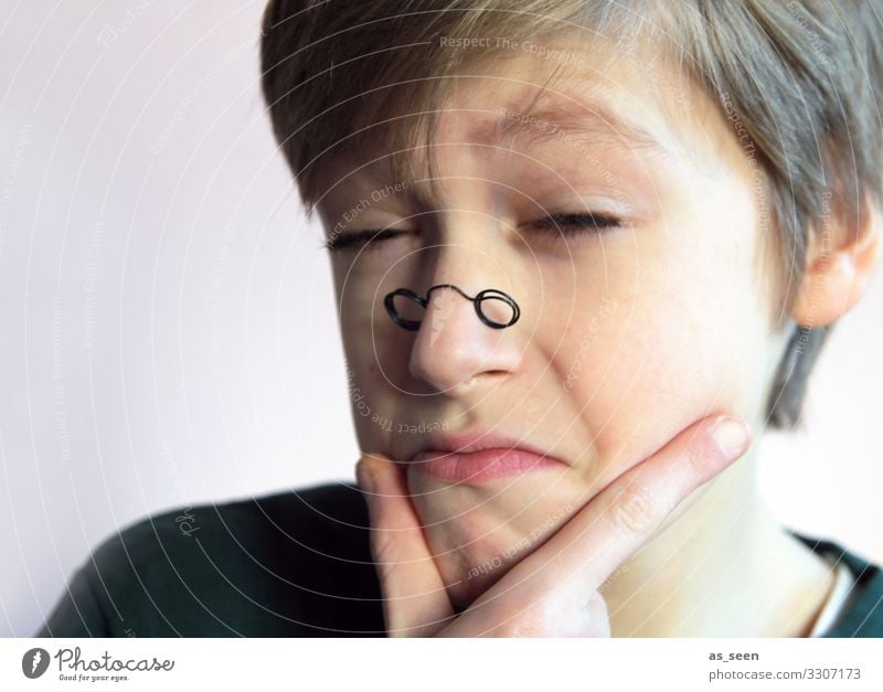 Boy looks through small glasses with sceptical eyes Looking monocle Eyeglasses Looking into the camera Portrait photograph Human being Masculine Face