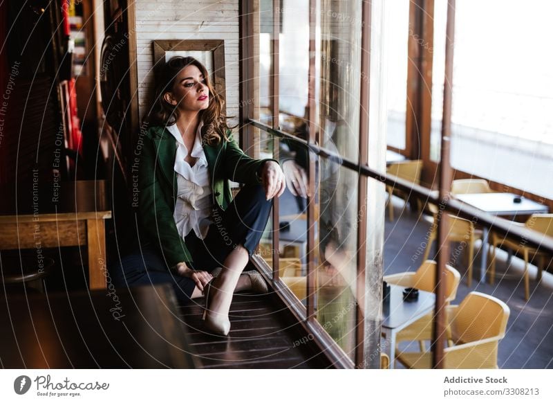 Thoughtful woman in stylish outfit in cafe fashionable trendy young casual lady female model wear clothes elegant charming accessories chic cafeteria lifestyle