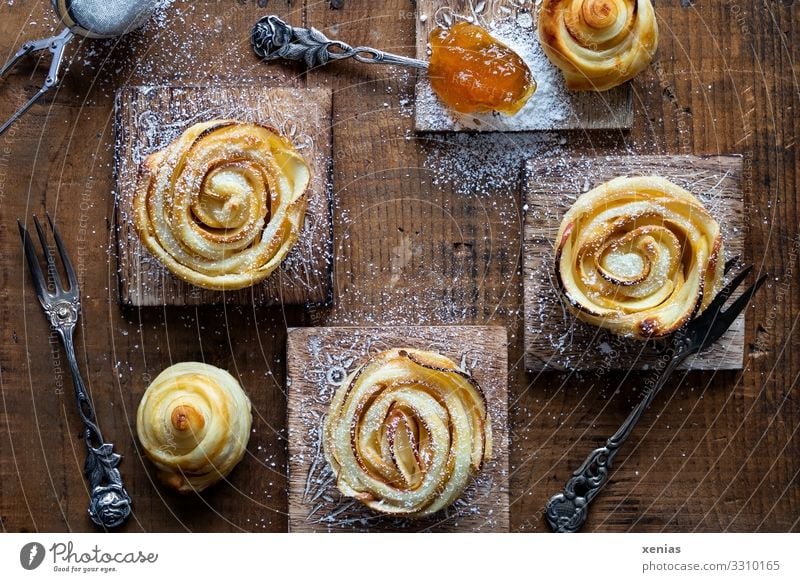 Three apple roses with icing sugar and apricot jam on wooden board Food Apple Dough Apple Rose Baked goods Cake Jam Confectioner`s sugar Apricot jam Nutrition