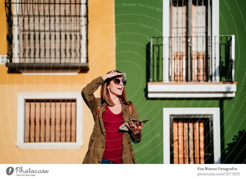 young woman reading a map over yellow and green background. travel concept Woman City Map Multicoloured Background picture Vacation & Travel Tourism Sunglasses