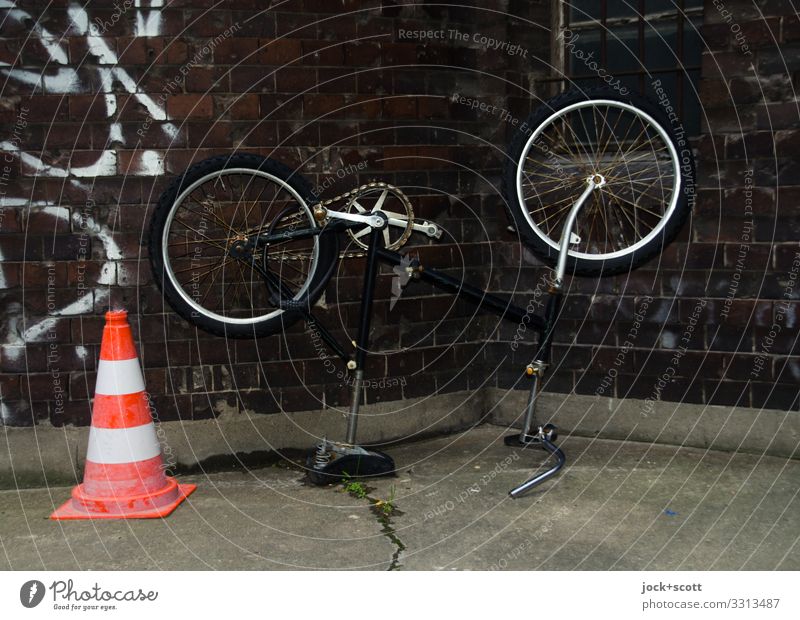 who turned the wheel? Design Prenzlauer Berg Wall (building) Backyard Traffic cone Graffiti Dark Gloomy Moody Safety Idea Problem solving Mountain bike