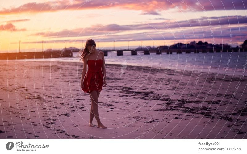 Young woman in a red dress in a beach young summer sand clouds ocean pristine coast tourism natural energy surf female people running wonderful light freedom