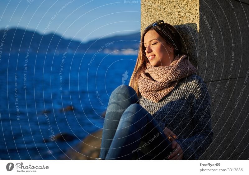 Young woman enjoying the sunlight near the ocean in Vigo young sea water rocks vigo galicia winter autumn blue travel enjoyment hiking coast coastal sky