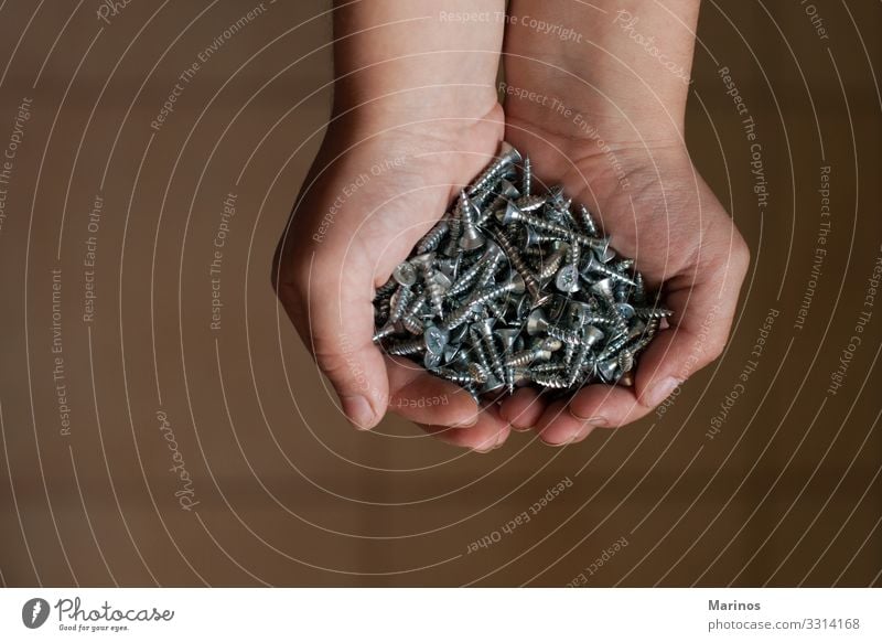 Man's hands hold several screws. Work and employment Industry Tool Human being Arm Hand Metal Strong Gray background equipment construction