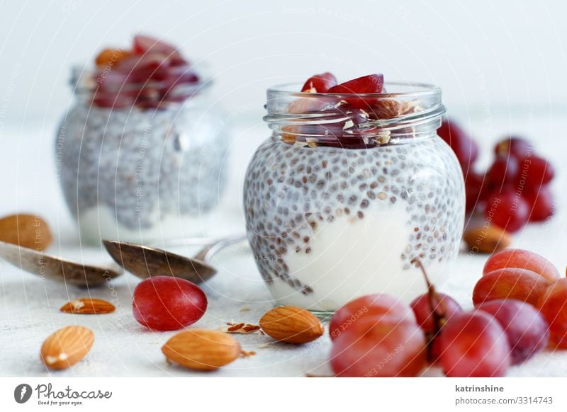 Chia pudding parfait with red grapes and almonds Yoghurt Fruit Dessert Eating Breakfast Diet Spoon Dark Gray White jar chia Bunch of grapes nuts Pudding seed