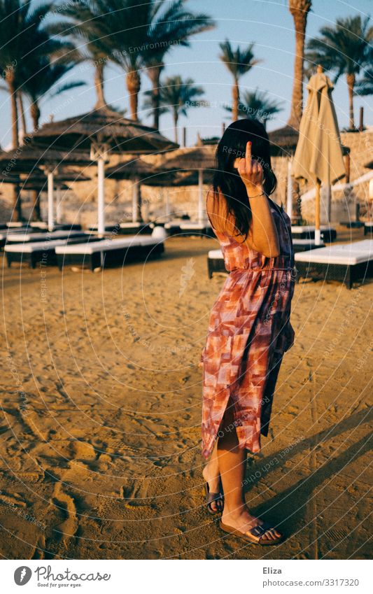 An annoyed woman on the beach on vacation, holding her middle finger in the camera Young woman Youth (Young adults) Woman Adults 18 - 30 years furious quarrel