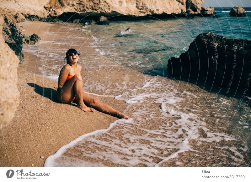 Young woman sitting on the beach by the sea and laughing into the camera Human being Feminine vacation Laughter Youth (Young adults) Woman Adults 18 - 30 years