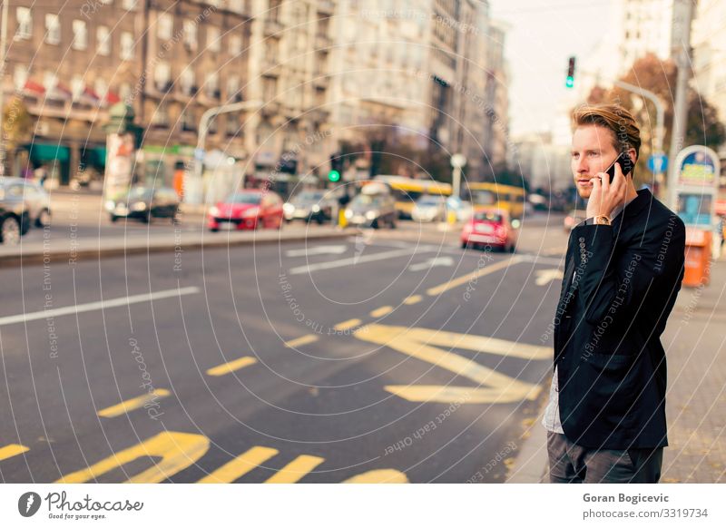 Young man on the street with mobile phone Lifestyle Telephone PDA Technology Human being Youth (Young adults) Man Adults Autumn Building Street Beard Stand