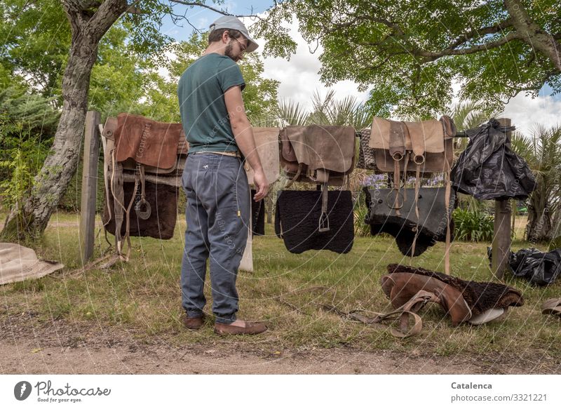 The young man thinks about how best to put the different parts of the saddles together person Man youthful masculine Stand Saddle Saddle parts Sweat blanket