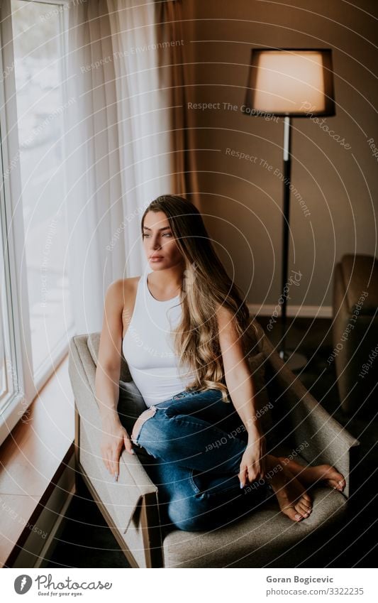 Beautiful young woman sitting by the window Lifestyle Relaxation Flat (apartment) House (Residential Structure) Human being Young woman Youth (Young adults)