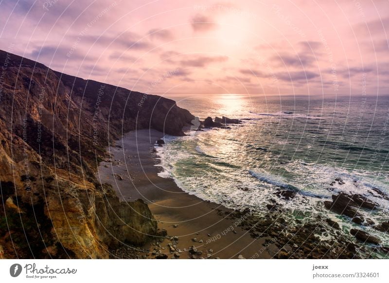 Steep coast with rocky beach and surf in front of pink clouds Ocean Waves Nature Landscape Sky Clouds Beautiful weather Rock Coast Gigantic Large Maritime Brown