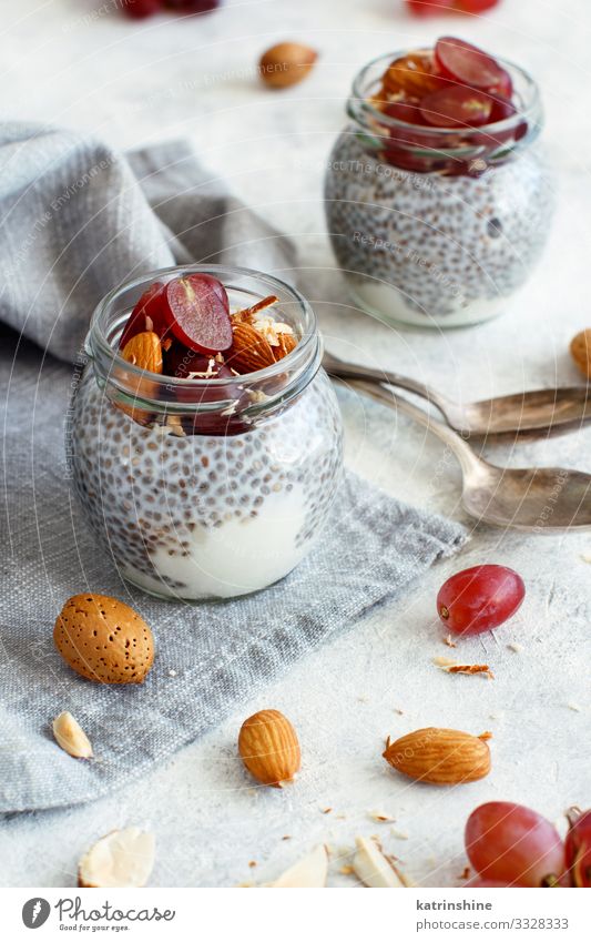 Chia pudding parfait with red grapes and almonds Yoghurt Fruit Dessert Eating Breakfast Diet Spoon White jar chia Bunch of grapes nuts Pudding seed chia seeds