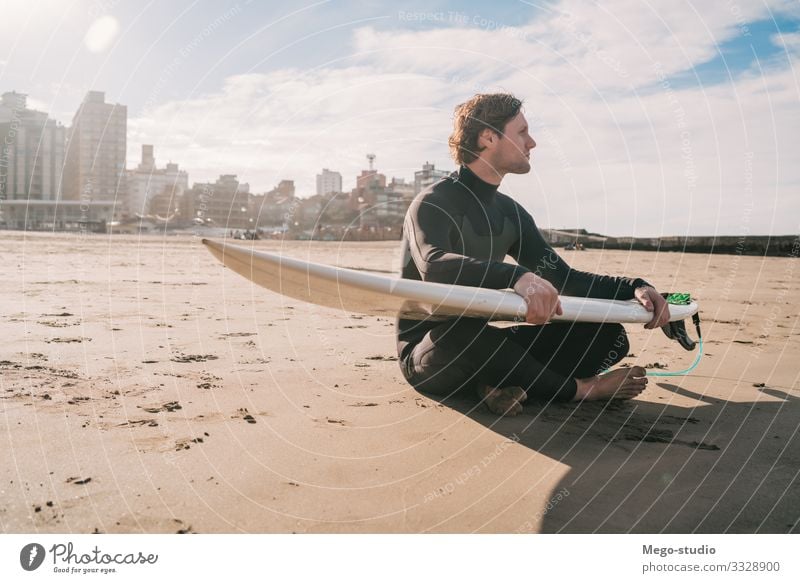 Surfer sitting on sandy beach with surfboard. Lifestyle Happy Relaxation Leisure and hobbies Adventure Beach Ocean Waves Sports Aquatics Human being Masculine