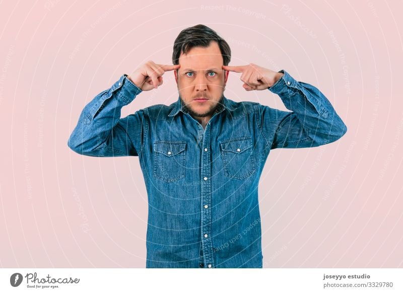 Young man with expression of concentration. pink background absorbed abstraction guess Concentrate Concreted Fingers self-absorbed Magic Meditation mentalist