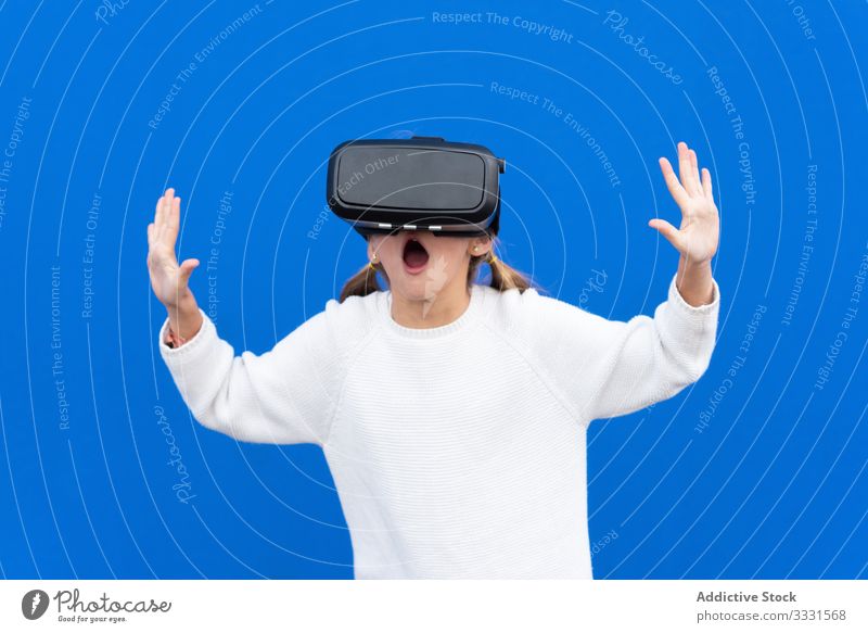 Positive girl playing VR at studio goggles vr kid excited wow amazed fun smile laugh casual child hand carefree happiness female astonishment colorful activity