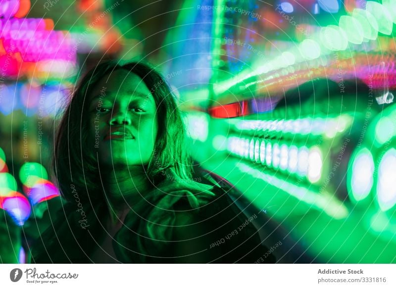 Cheerful black woman on funfair smile night arcade illumination sit rest weekend ethnic female amusement attraction colorful joy happy cheerful bright lady