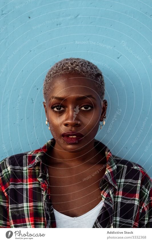 Young black short haired woman looking at camera with intense look female sad portrait challenge piercing plaid shirt african american young unhappy upset