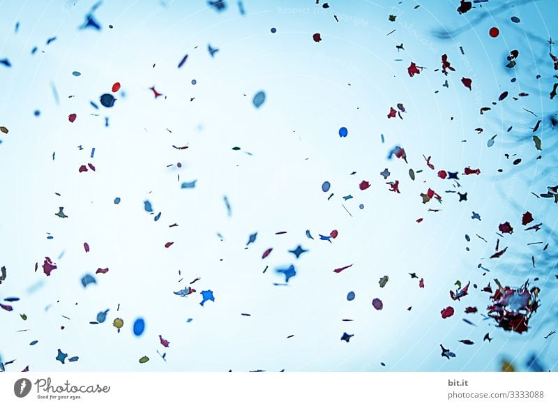 A lot of colourful confetti flies dynamically at carnival, carnival, fancy dress party, celebration in the air, in front of a blue sky and swirls merrily.