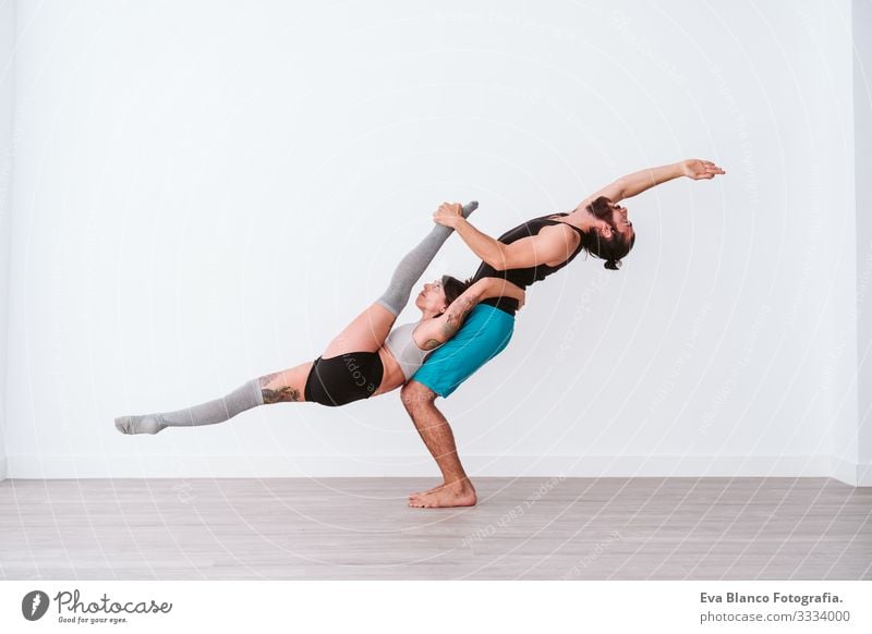 young couple Couple practicing acro yoga in white studio or gym. Healthy lifestyle Yoga Sports Gymnasium indoor Man Power Human being human relationships