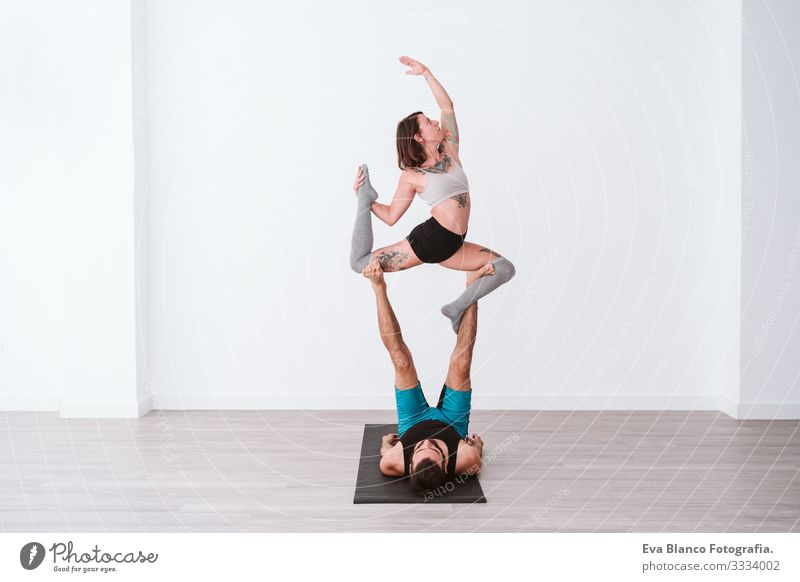 young couple Couple practicing acro yoga in white studio or gym. Healthy lifestyle Yoga Sports Gymnasium indoor Man Power Human being human relationships