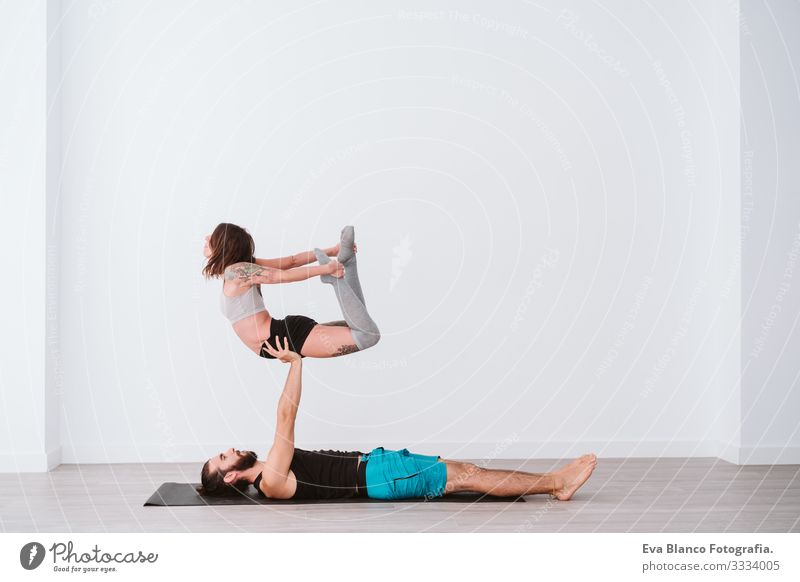 young couple Couple practicing acro yoga in white studio or gym. Healthy lifestyle Yoga Sports Gymnasium indoor Man Power Human being human relationships