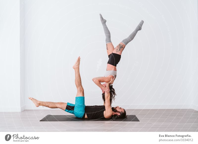 young couple Couple practicing acro yoga in white studio or gym. Healthy lifestyle Yoga Sports Gymnasium indoor Man Power Human being human relationships