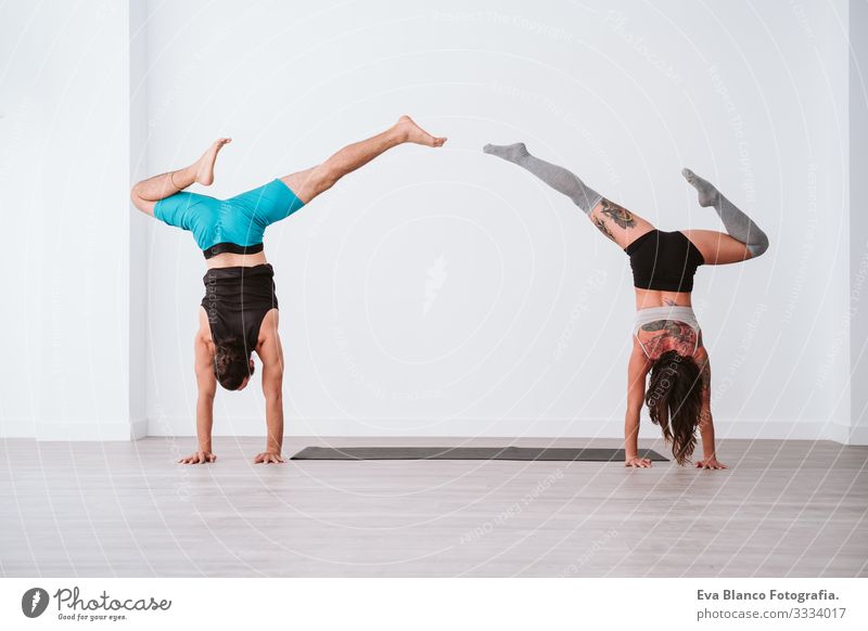 young couple Couple practicing acro yoga in white studio or gym. Healthy lifestyle Yoga Sports Gymnasium indoor Man Power Human being human relationships