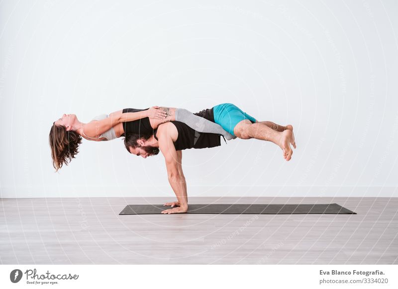 young couple Couple practicing acro yoga in white studio or gym. Healthy lifestyle Yoga Sports Gymnasium indoor Man Power Human being human relationships