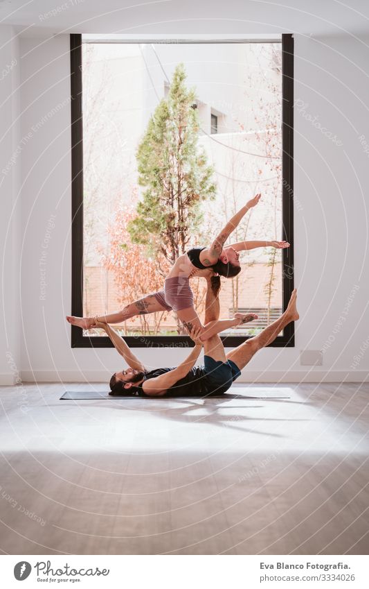 young couple Couple practicing acro yoga by the window in studio or gym. Healthy lifestyle Yoga Sports Gymnasium indoor Man Power Human being