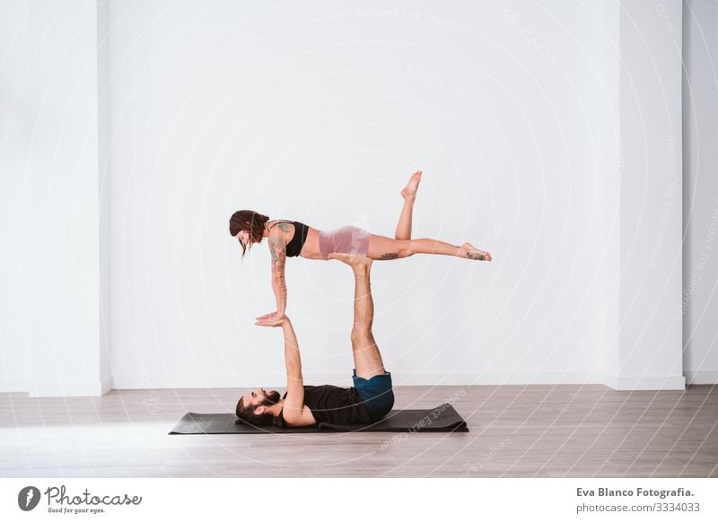 young couple Couple practicing acro yoga in white studio or gym. Healthy lifestyle Yoga Sports Gymnasium indoor Man Power Human being human relationships