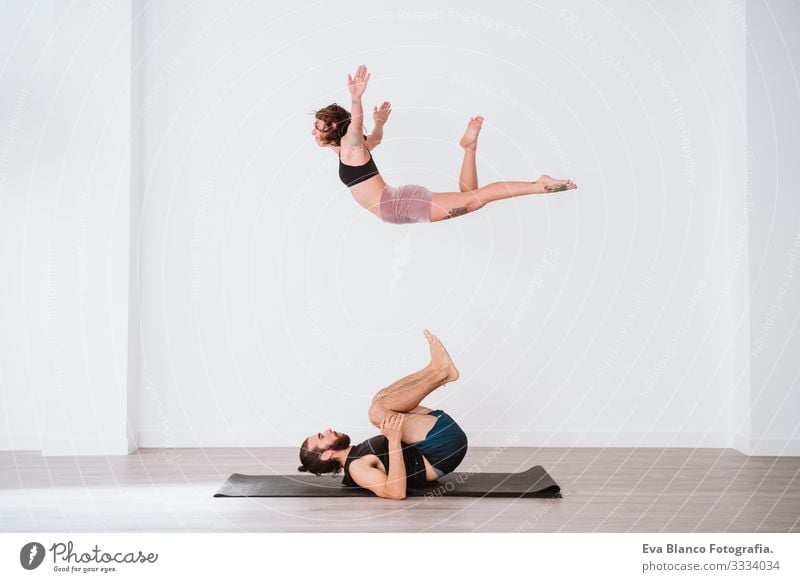 young couple Couple practicing acro yoga in white studio or gym. Healthy lifestyle Yoga Sports Gymnasium indoor Man Power Human being human relationships