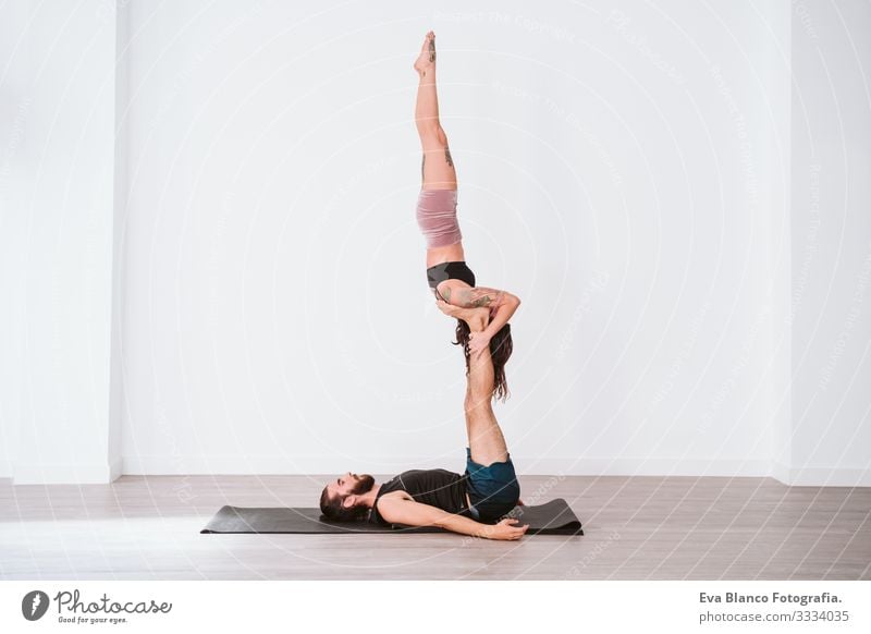 young couple Couple practicing acro yoga in white studio or gym. Healthy lifestyle Yoga Sports Gymnasium indoor Man Power Human being human relationships