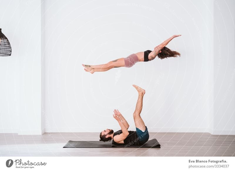 young couple Couple practicing acro yoga in white studio or gym. Healthy lifestyle Yoga Sports Gymnasium indoor Man Power Human being human relationships