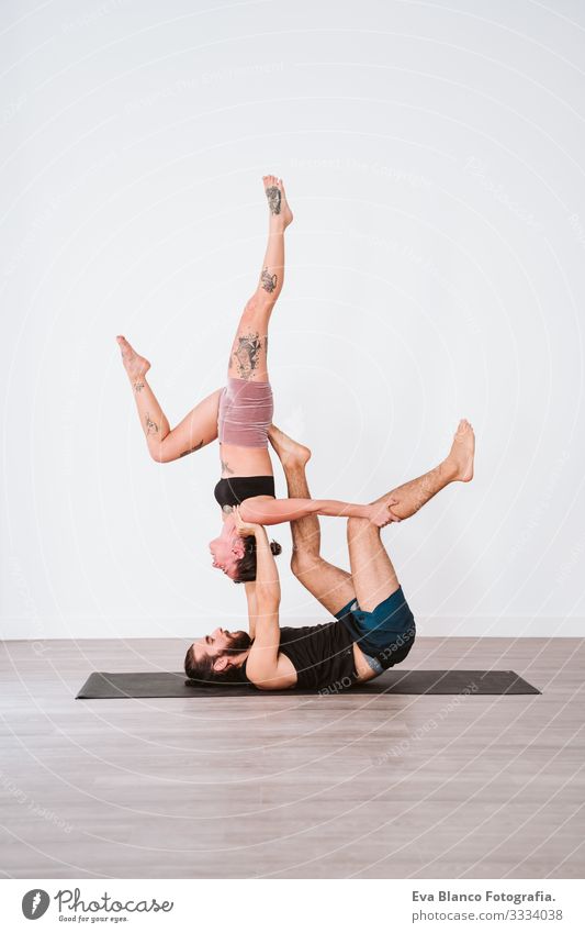 young couple Couple practicing acro yoga in white studio or gym. Healthy lifestyle Yoga Sports Gymnasium indoor Man Power Human being human relationships