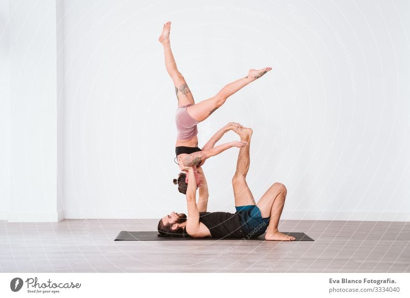 young couple Couple practicing acro yoga in white studio or gym. Healthy lifestyle Yoga Sports Gymnasium indoor Man Power Human being human relationships