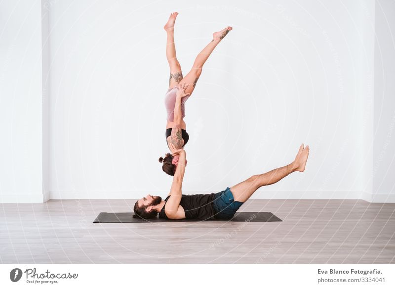 young couple Couple practicing acro yoga in white studio or gym. Healthy lifestyle Yoga Sports Gymnasium indoor Man Power Human being human relationships