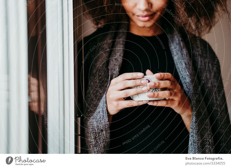 portrait of beautiful afro american young woman by the window holding a cup of coffee. Lifestyle indoors African-American Woman Coffee Home Ethnic