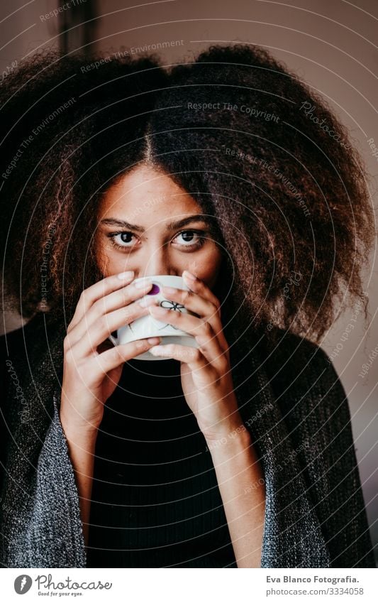 portrait of beautiful afro american young woman by the window drinking tea or coffee. Lifestyle indoors African-American Woman Coffee Home Ethnic